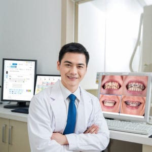 Dentist using EMR system Malaysia with dental records on screen